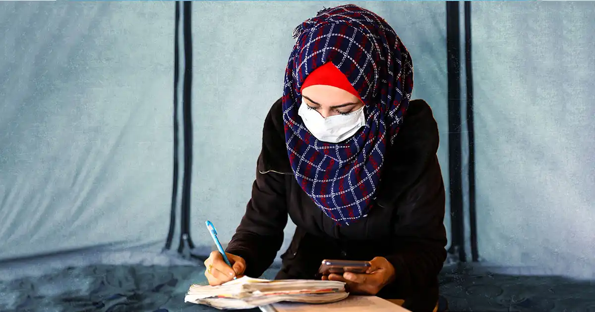 عائشة طالبة من طلاب مبادرة مسارات تدرس في مخيمات النزوح شمال غرب سوريا لم يمنعها المخيم من متابعة تحصيلها العلمي، تظهر ممسكة كتابا